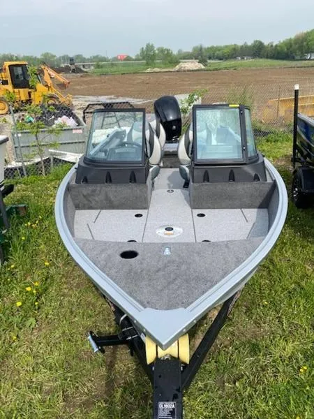 Slide: The Image of 2022 Alumacraft Voyageur 175 Sport boat on grassy area, with dual windshields. - 6