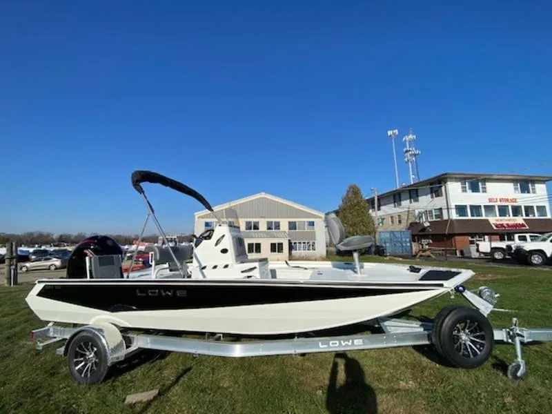 Slide: The Image of 2023 Lowe Bay20 boat on trailer, parked outdoors under clear blue sky. - 10