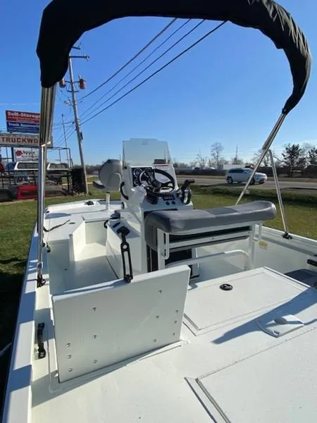 Slide: The Image of 2023 Lowe Bay20 boat with canopy, steering console, and seating, displayed outdoors. - 15