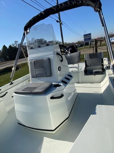 Slide: The Image of 2023 Lowe Bay20 boat with seating and console, parked outdoors under clear sky. - 16