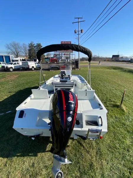 Slide: The Image of 2023 Lowe Bay20 boat with outboard motor, parked on grass, under clear blue sky. - 18