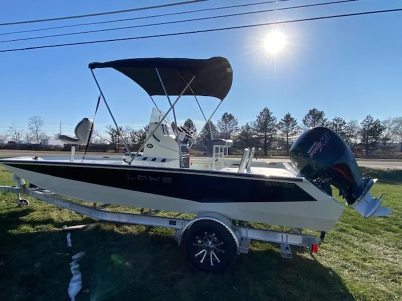 Slide: The Image of 2023 Lowe Bay20 boat on trailer, sunny day, grassy area, trees in background. - 2