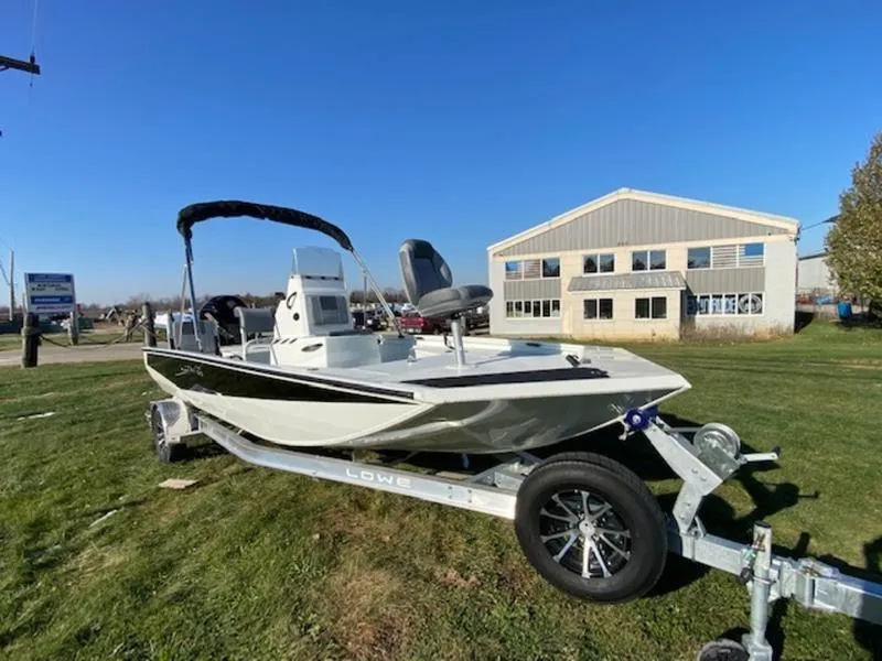 Slide: The Image of 2023 Lowe Bay20 boat on trailer, parked on grass near industrial building. - 5