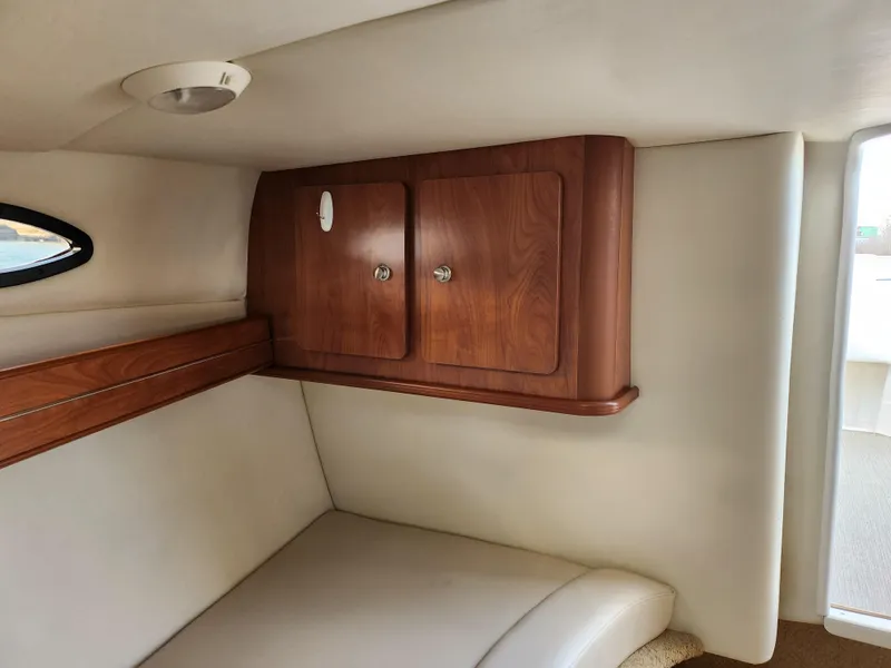 Slide: The Image of 2007 Rinker 246 Captiva Cuddy cabin interior with wood cabinets and cushioned seating. - 22
