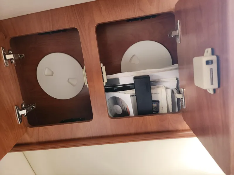 Slide: The Image of 2007 Rinker 246 Captiva Cuddy interior storage compartments with wooden finish and documents. - 23