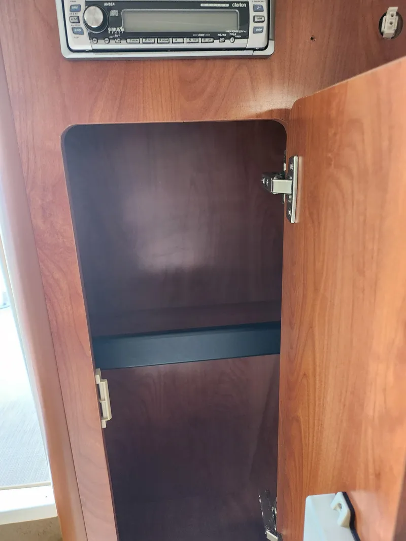 Slide: The Image of Open wooden cabinet in 2007 Rinker 246 Captiva Cuddy boat interior. - 25