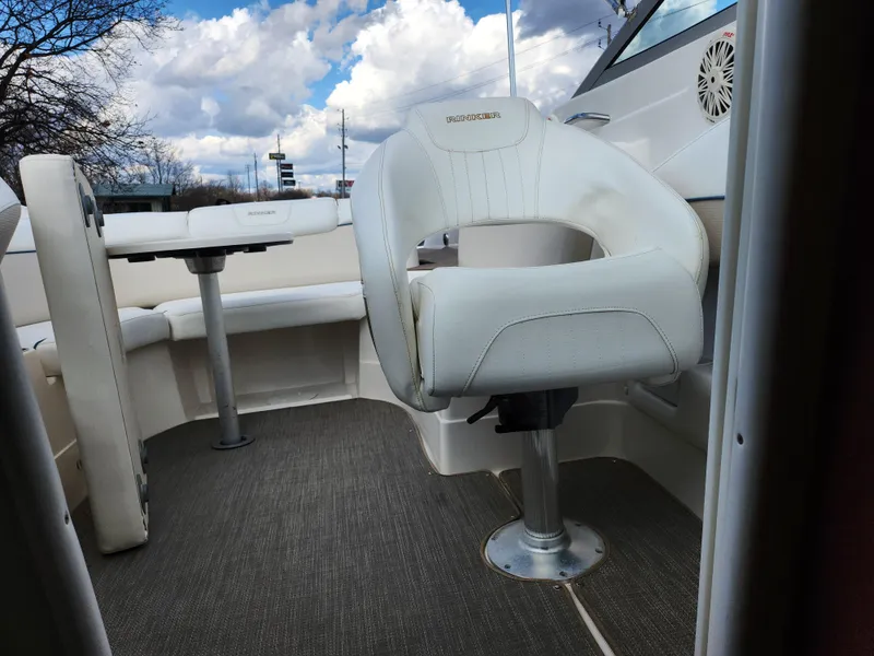 Slide: The Image of 2007 Rinker 246 Captiva Cuddy interior with white seating and table under cloudy sky. - 27