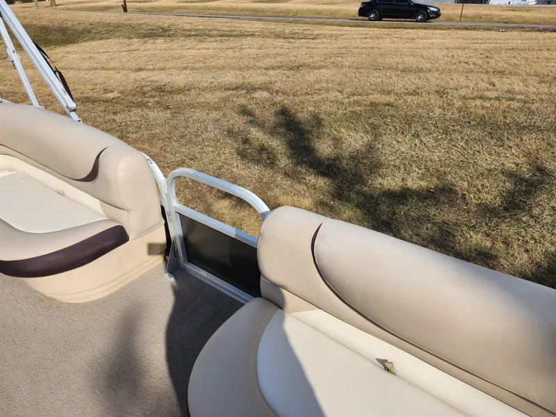 Slide: The Image of 2015 Sun Tracker Party Barge 20 DLX with beige seating, parked on grass. - 12