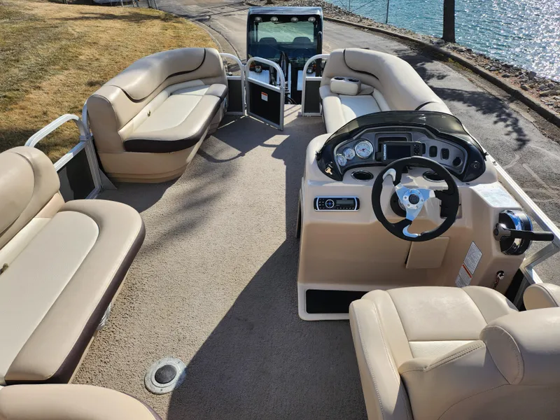 Slide: The Image of 2015 Sun Tracker Party Barge 20 DLX interior with beige seating and steering console. - 20
