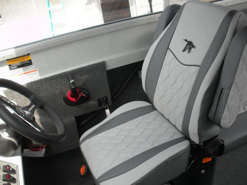 Slide: The Image of Captain's seat in 2025 Duckworth 24 Pacific Pro boat, featuring gray upholstery and steering wheel. - 14
