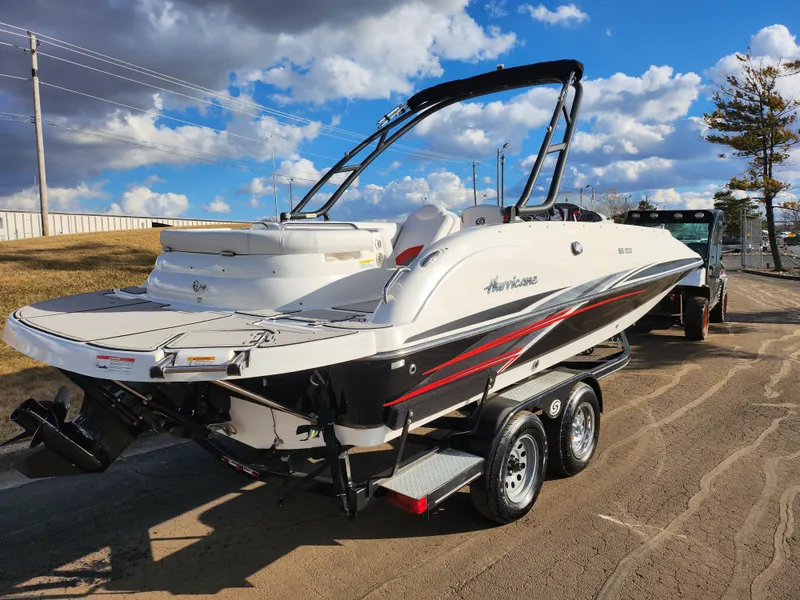 Slide: The Image of 2019 Hurricane SunDeck Sport 202 IO boat on trailer, parked outdoors under a blue sky. - 3