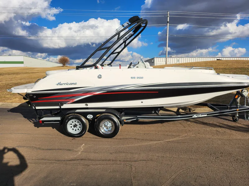 Slide: The Image of 2019 Hurricane SunDeck Sport 202 IO boat on trailer, parked outdoors under cloudy sky. - 4