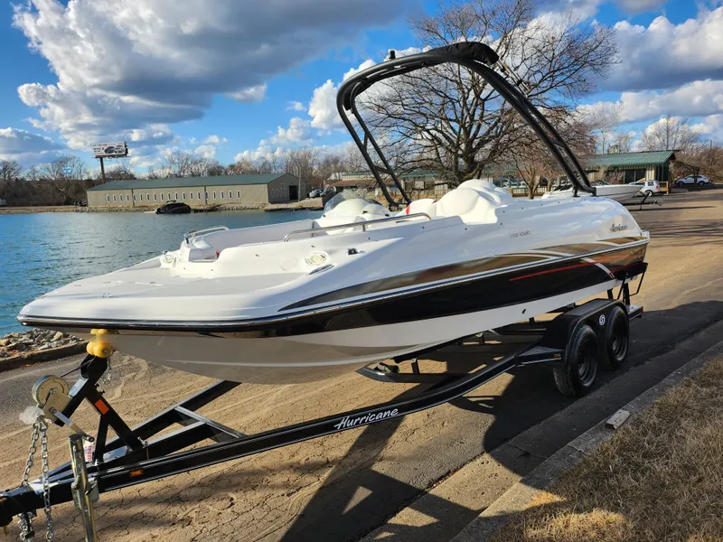 Slide: The Image of 2019 Hurricane SunDeck Sport 202 IO boat on trailer by a lake under a cloudy sky. - 8
