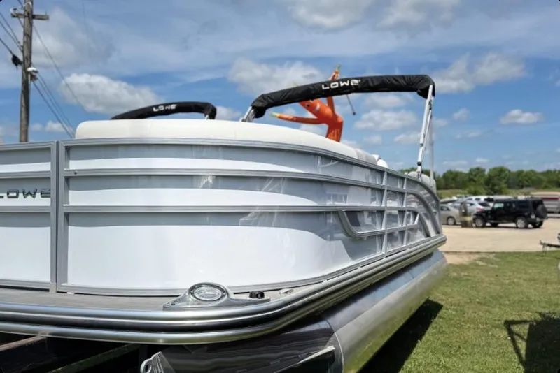 Slide: The Image of 2023 Lowe SS 210 WT pontoon boat displayed outdoors under a blue sky. - 0