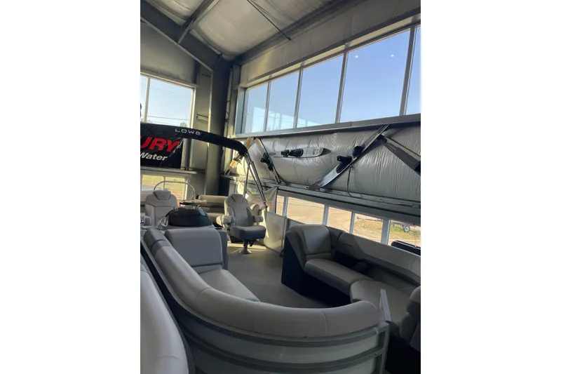 Slide: The Image of 2023 Lowe SS 210 WT pontoon boat interior with plush seating in a showroom. - 1