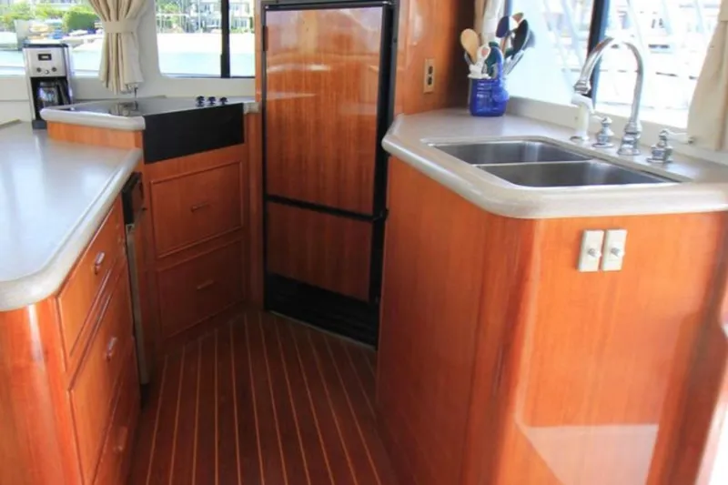 Slide: The Image of Kitchen area of a 1997 Mediterranean 54 Convertible yacht with wood cabinetry and dual sinks. - 3