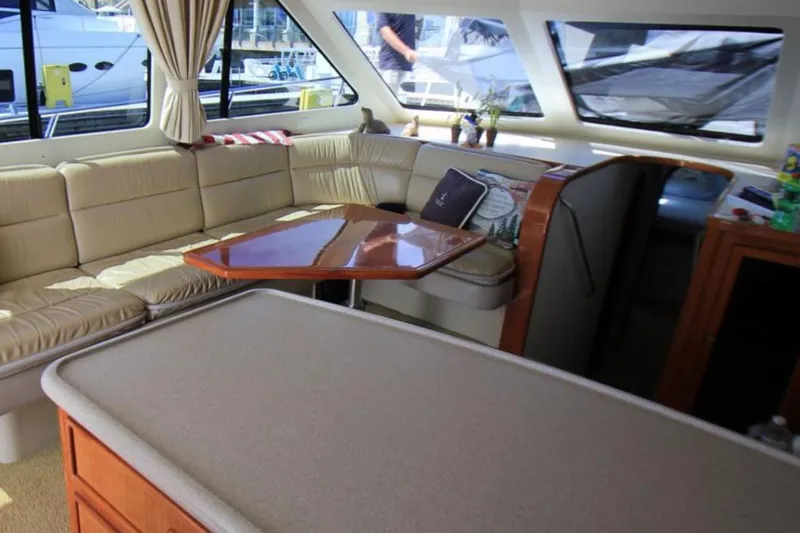 Slide: The Image of Luxurious interior of a 1997 Mediterranean 54 Convertible yacht with beige seating and wooden table. - 4