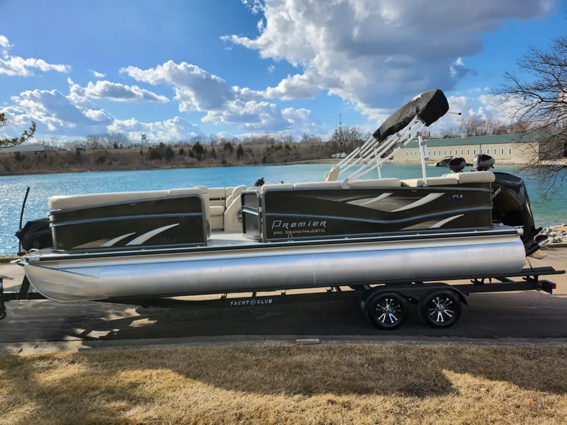 Slide: The Image of 2019 Premier 250 Grand Majestic RE pontoon boat on trailer by a lake. - 10