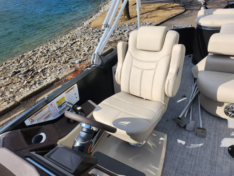 Slide: The Image of Captain's chair on 2019 Premier 250 Grand Majestic RE pontoon boat, near rocky shoreline. - 15