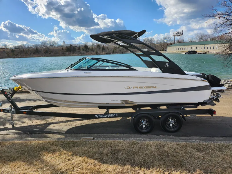Slide: The Image of 2021 Regal LS2 boat on trailer by a lake under a cloudy sky. - 9