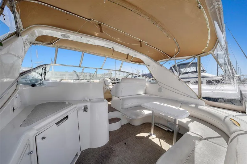 Slide: The Image of 1999 Cruisers Yachts 3870 Esprit interior with white seating and helm, under tan canopy. - 12