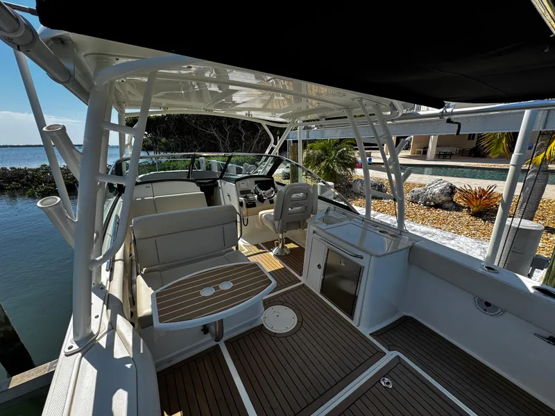 Slide: The Image of 2019 Boston Whaler 270 Vantage boat interior with seating and helm, docked by the water. - 14