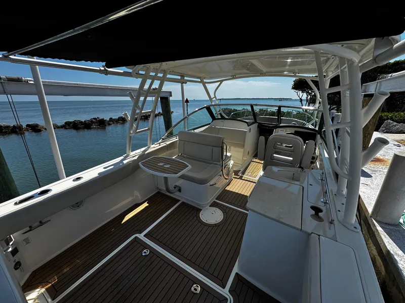 Slide: The Image of 2019 Boston Whaler 270 Vantage boat interior with seating and table, docked by the water. - 15