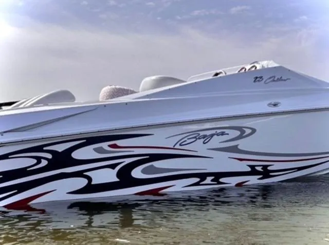 Slide: The Image of 2006 Baja 23 Outlaw boat with sleek graphics on calm water. - 3