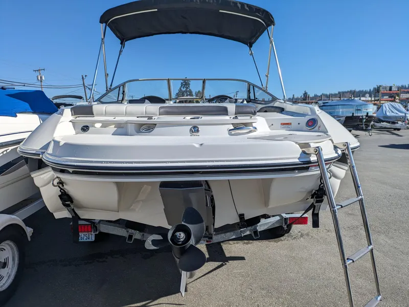 Slide: The Image of 2018 Stingray 208 LS boat with ladder and canopy, parked outdoors. - 13