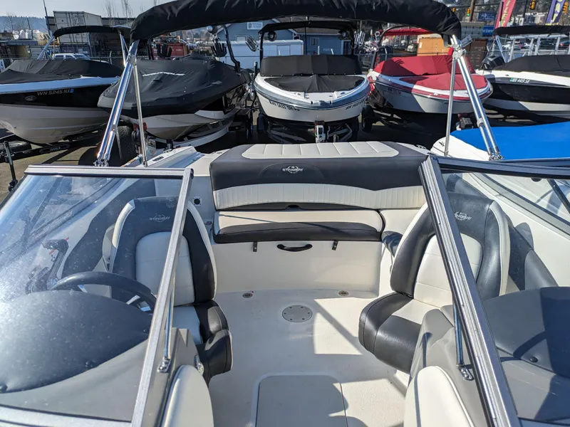Slide: The Image of 2018 Stingray 208 LS boat interior with seating, docked among other boats. - 17