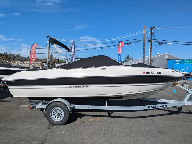 Slide: The Image of 2018 Stingray 208 LS boat on trailer, parked outdoors under clear blue sky. - 5