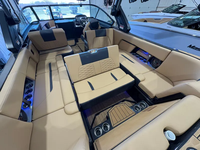 Slide: The Image of 2022 MasterCraft X26 boat interior with tan seating and wood accents. - 10