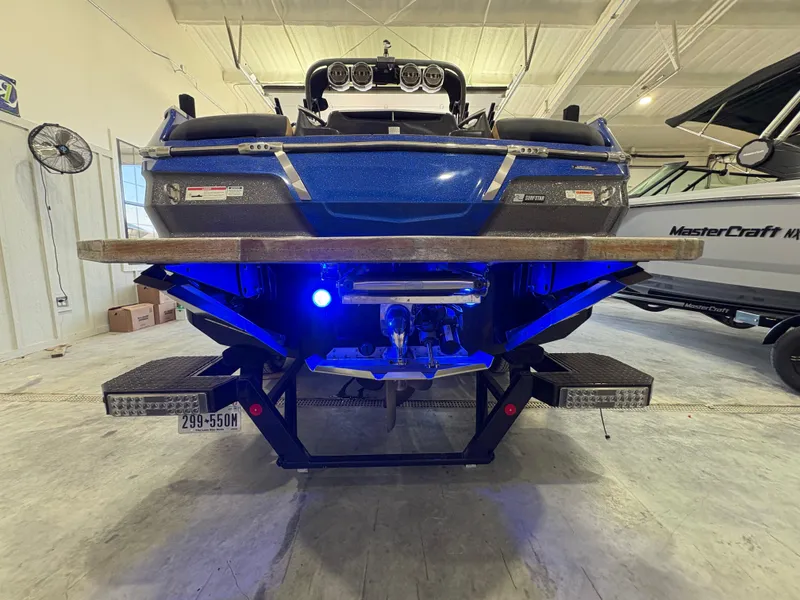 Slide: The Image of 2022 MasterCraft X26 boat in showroom, black exterior, tan interior, front view. - 9