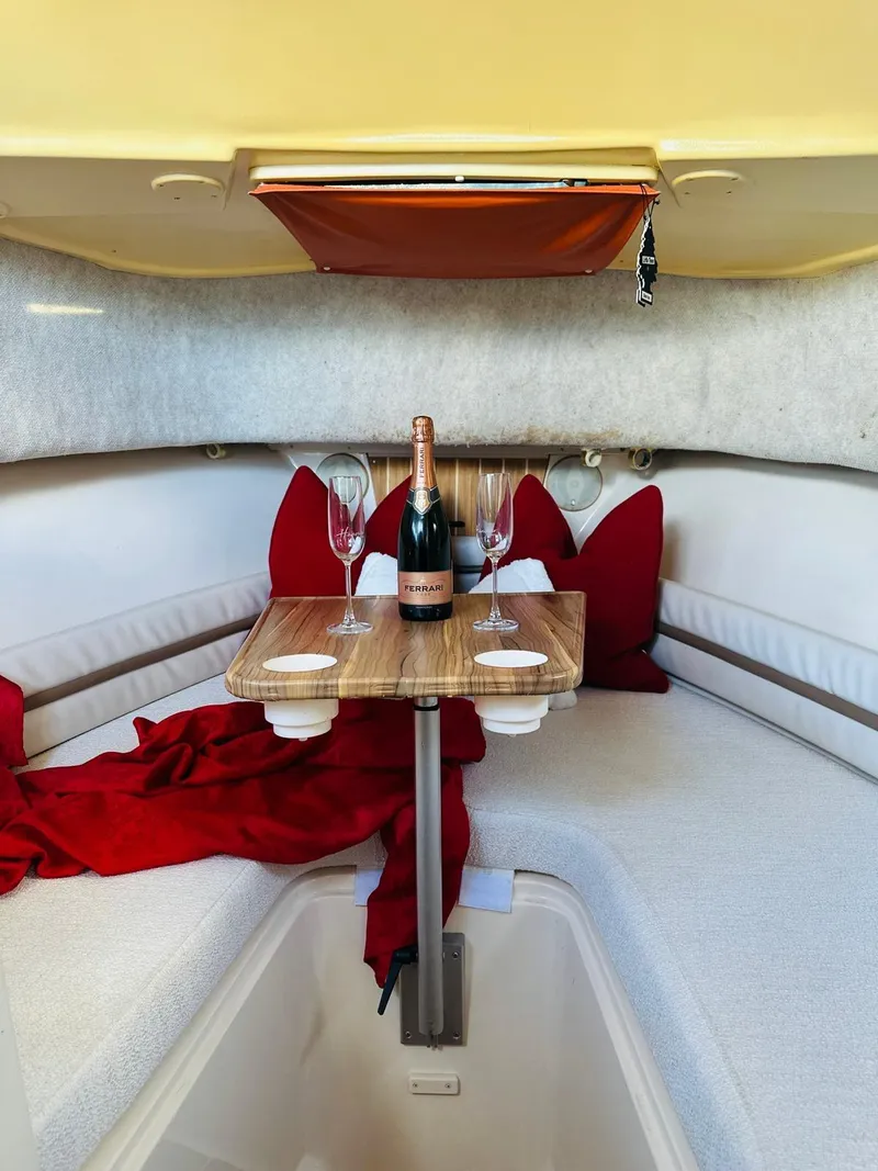 Slide: The Image of 2001 Grady-White Sailfish 282 cabin with table, champagne, and red accents. Cozy and inviting interior. - 11