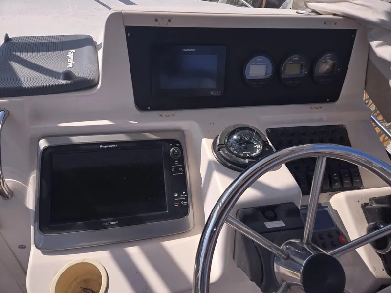 Slide: The Image of 2001 Grady-White Sailfish 282 dashboard with steering wheel, compass, and navigation equipment. - 16