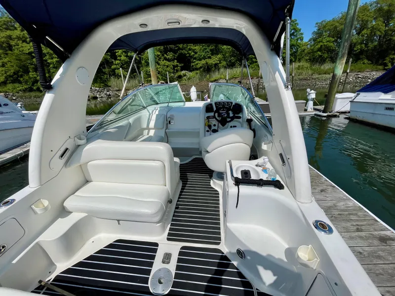 Slide: The Image of 2004 Sea Ray 260 Sundancer boat interior with seating and helm, docked at marina. - 2