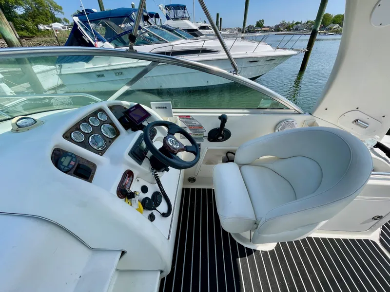 Slide: The Image of 2004 Sea Ray 260 Sundancer cockpit with steering wheel and controls, docked by the water. - 3