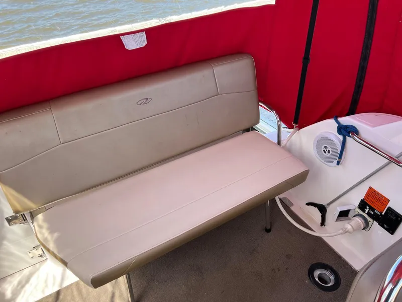 Slide: The Image of 2010 Regal 2565 Window Express boat interior with beige seating and red canopy. - 4