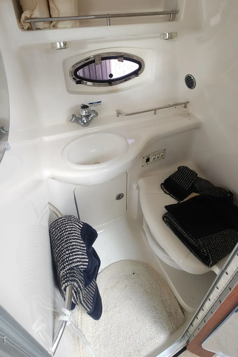 Slide: The Image of 2004 Chaparral Signature 290 bathroom with sink, toilet, and porthole window. - 14