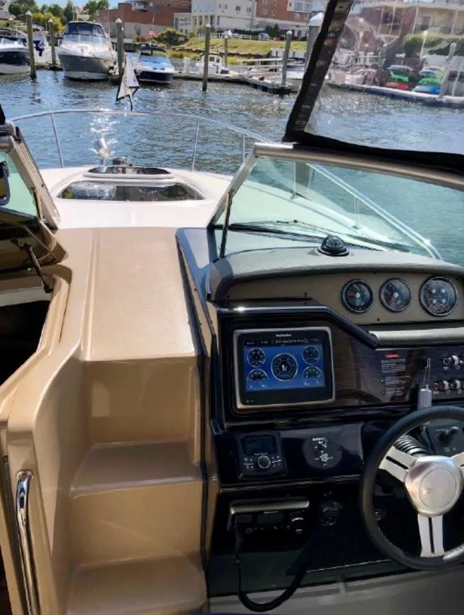 Slide: The Image of 2017 Sea Ray Sundancer 280 helm with modern controls, docked in a marina. - 2