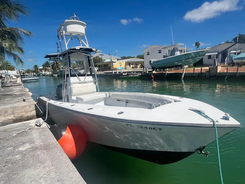 Slide: The Image of 1984 SeaVee 25 boat docked in a sunny marina, featuring a tower and calm waters. - 0