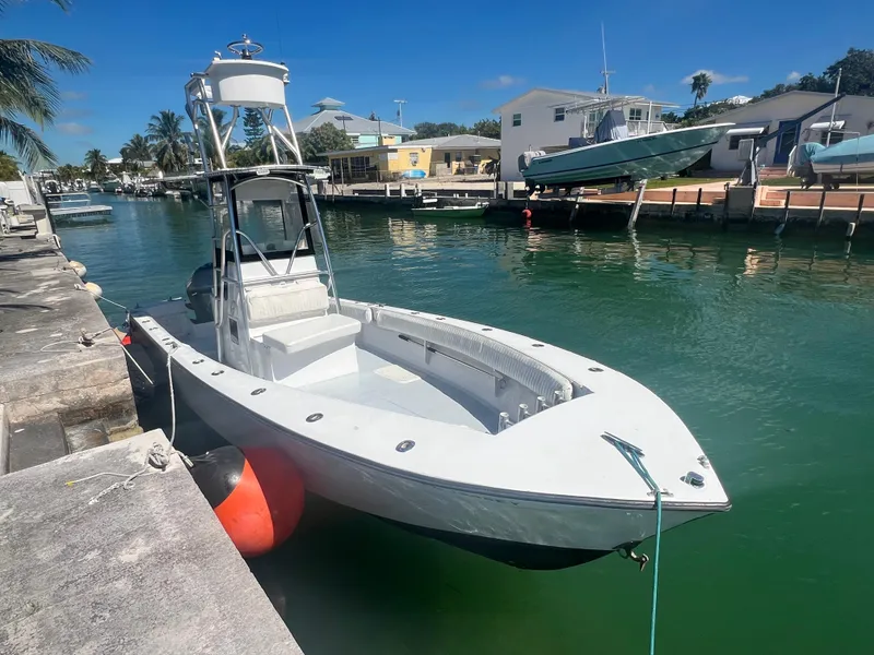 Slide: The Image of 1984 SeaVee 25 boat docked in a sunny canal, featuring a tower and open deck. - 2
