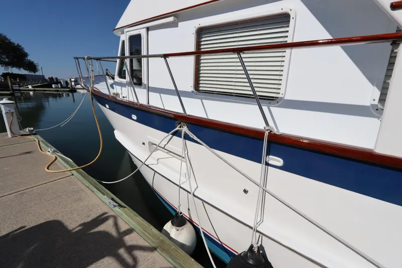 Slide: The Image of 1985 DeFever 44 Trawler docked, showcasing side view with fenders and railing. - 10
