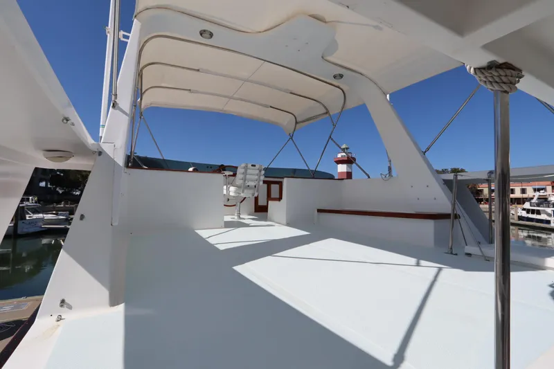 Slide: The Image of 1985 DeFever 44 Trawler flybridge with seating, under a canopy, in a marina setting. - 16