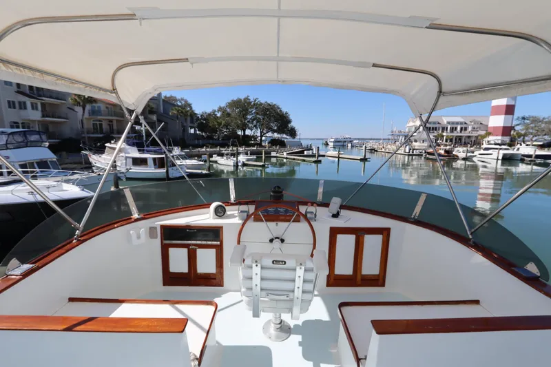 Slide: The Image of 1985 DeFever 44 Trawler helm view at marina, showcasing classic design and waterfront setting. - 17