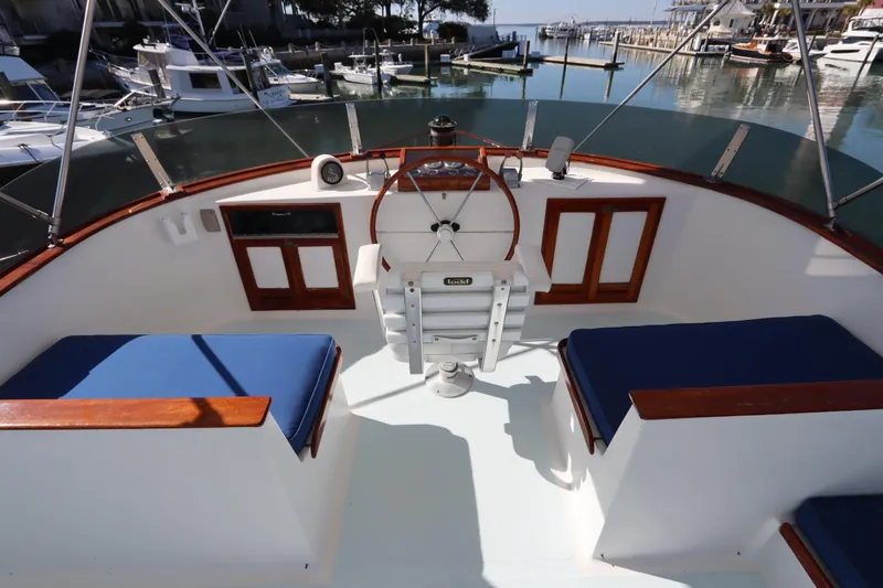 Slide: The Image of 1985 DeFever 44 Trawler helm with blue seating, overlooking marina. - 32