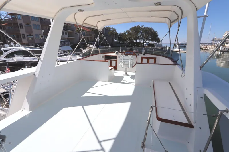 Slide: The Image of 1985 DeFever 44 Trawler flybridge with seating, docked at marina under clear skies. - 38