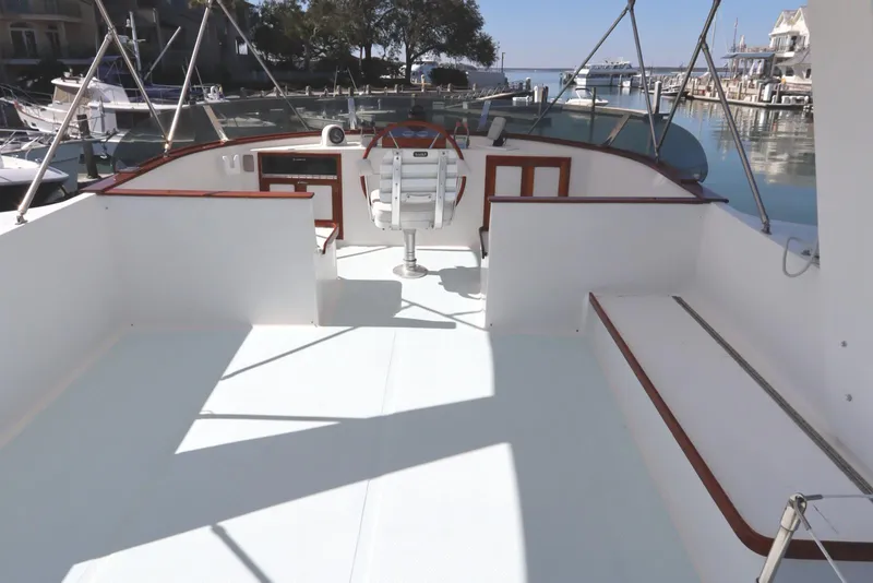 Slide: The Image of 1985 DeFever 44 Trawler flybridge with helm, seating, and marina view. - 39
