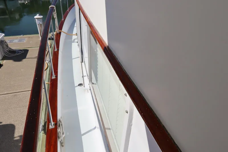 Slide: The Image of 1985 DeFever 44 Trawler deck with polished wood railing at marina. - 46