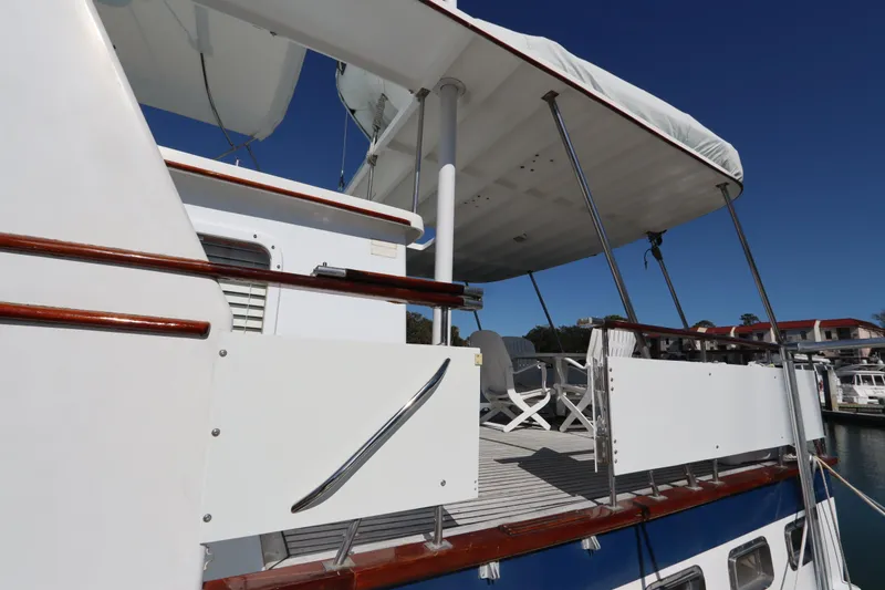 Slide: The Image of 1985 DeFever 44 Trawler yacht deck with seating, featuring white and blue accents. - 9